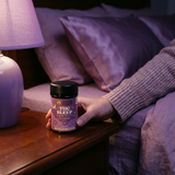 Hand holding Cypress Hemp Sleep Gummies on nightstand at bedside