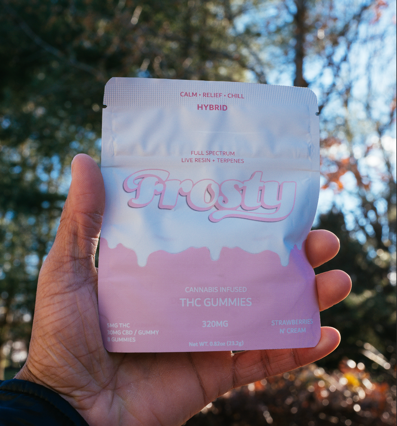 Hand holding Frosty Strawberries N Cream Hybrid gummies pouch outdoors